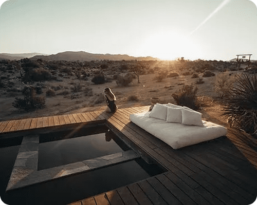 A person sitting on a deck with pillows and water