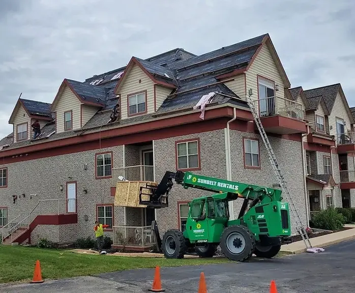 A green crane is parked in front of a building.