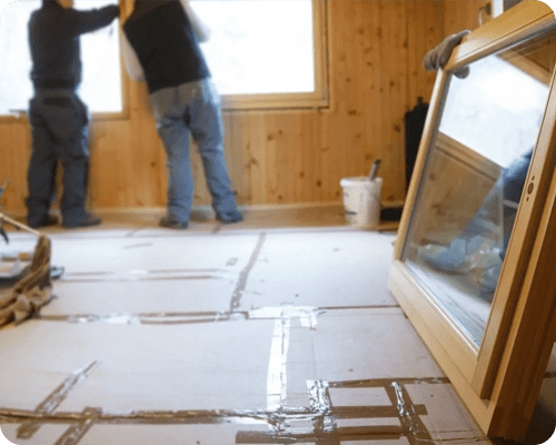 Two people standing in a room with some windows