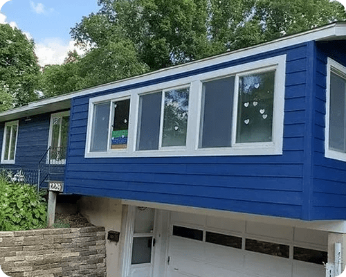 A blue house with a garage door and windows.