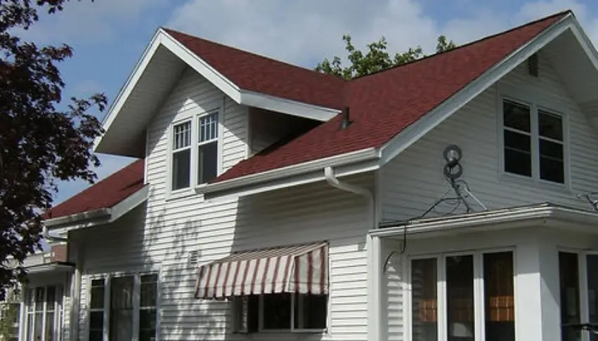 A white house with red roof and awning.